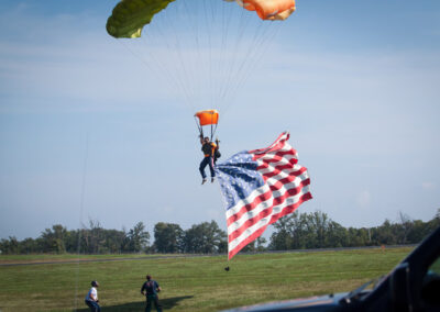 man parachuting into air show with American flag