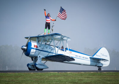 Dave Day Airshow - man standing on top of plane with American flag